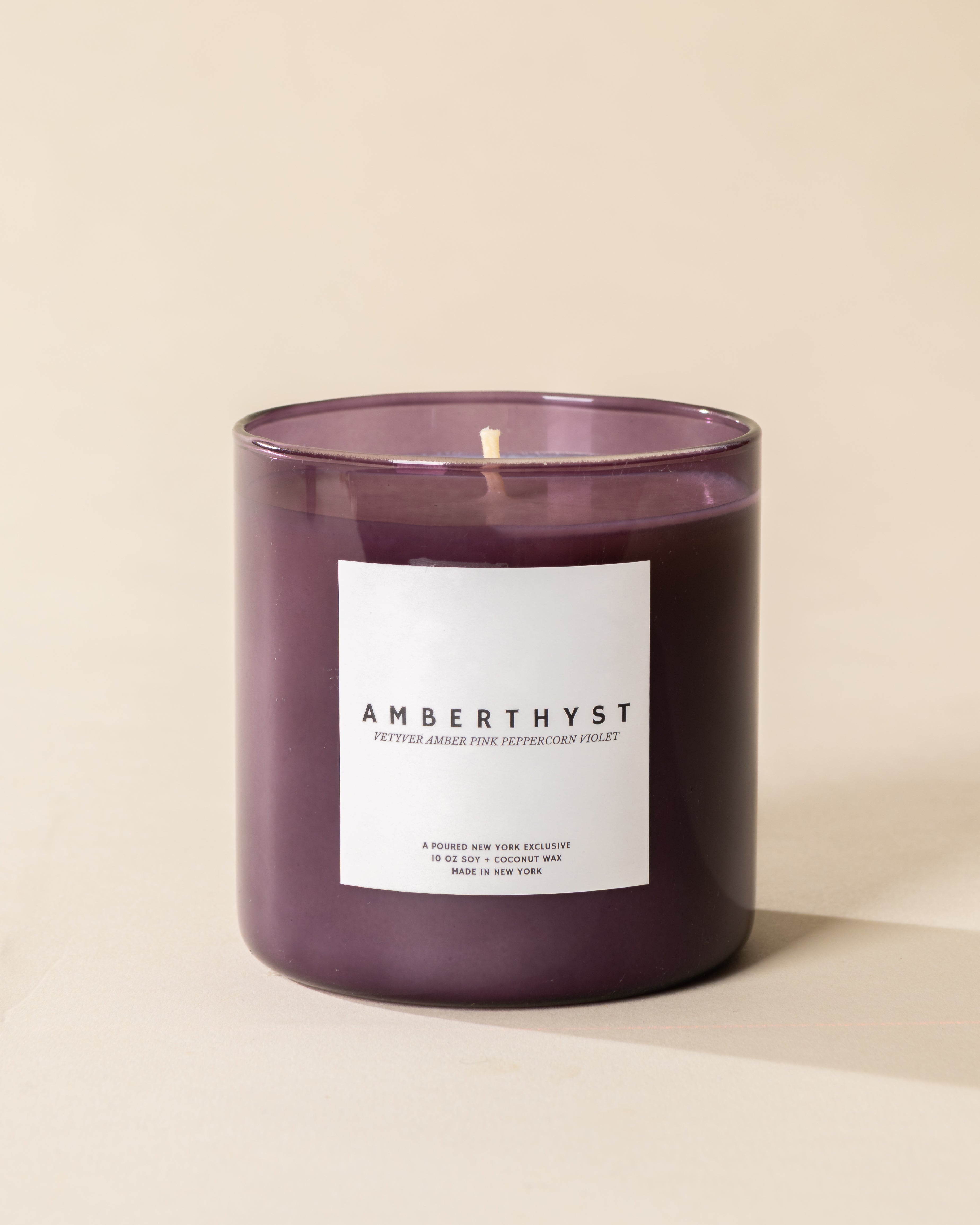 Poured New York 'Amberthyst' 10 oz purple glass soy coconut wax candle on a neutral background