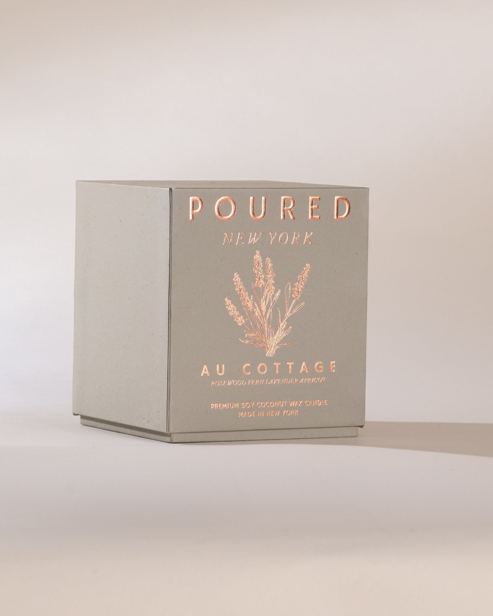 Poured New York 'Au Cottage' grey candle box and lavender decal on a neutral background