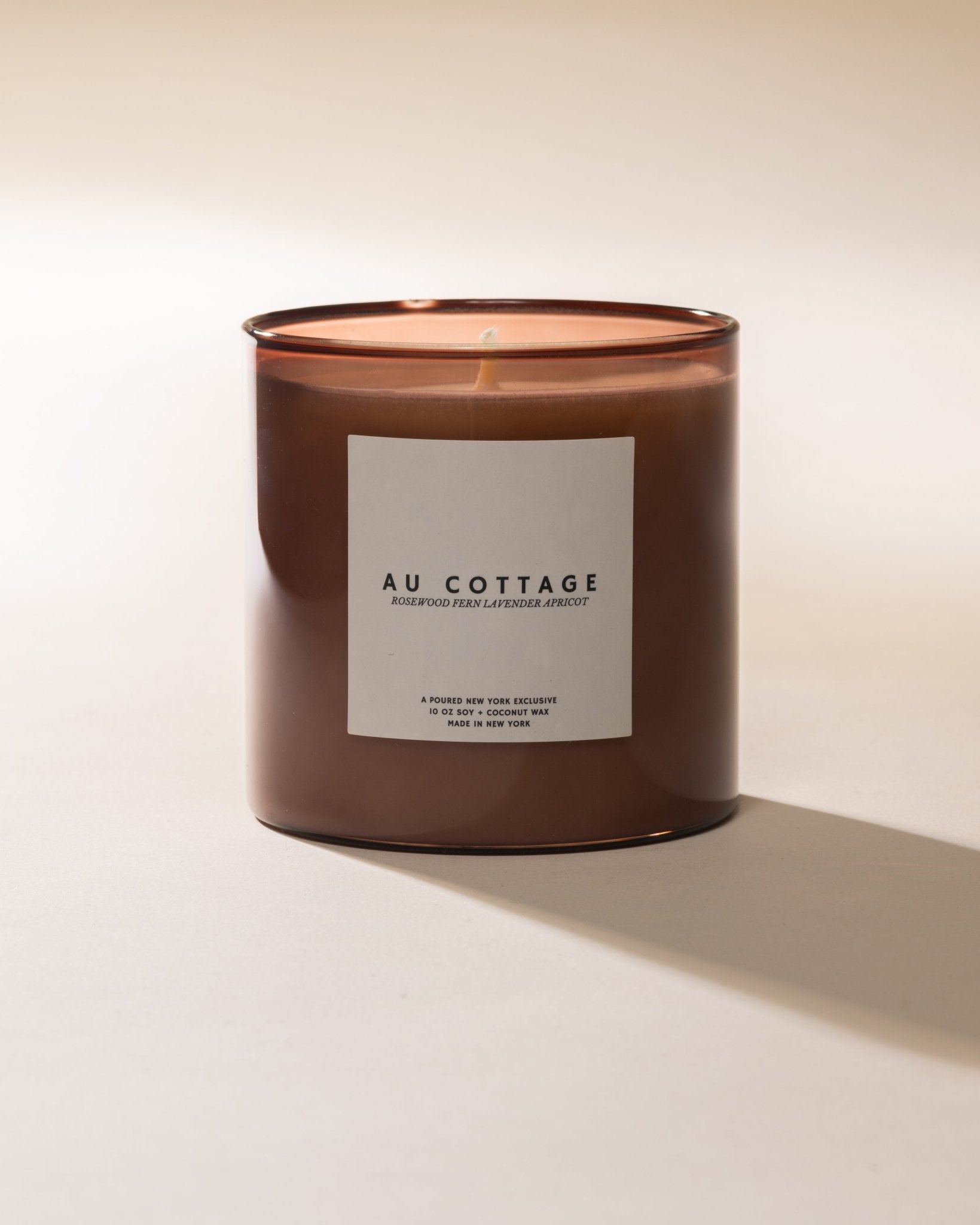 Poured New York 'Au Cottage' nude colored glass candle on a neutral background