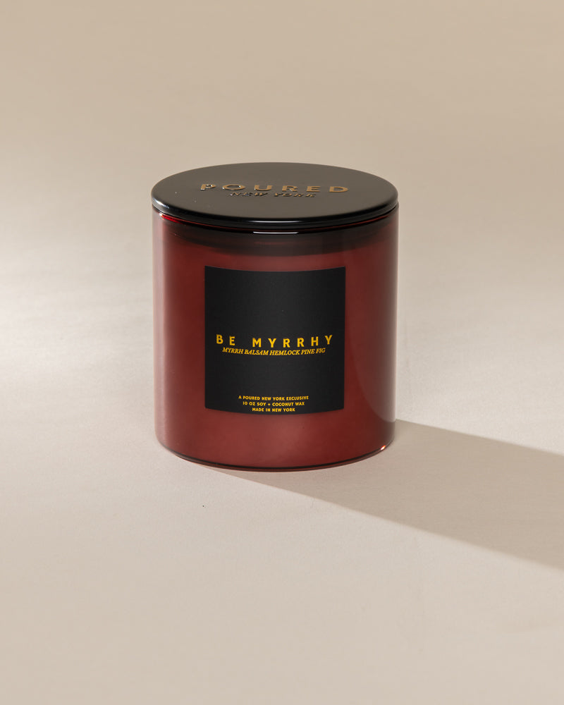 Poured New York 'Be Myrrhy' 10 oz red glass coconut soy wax candle on a neutral background