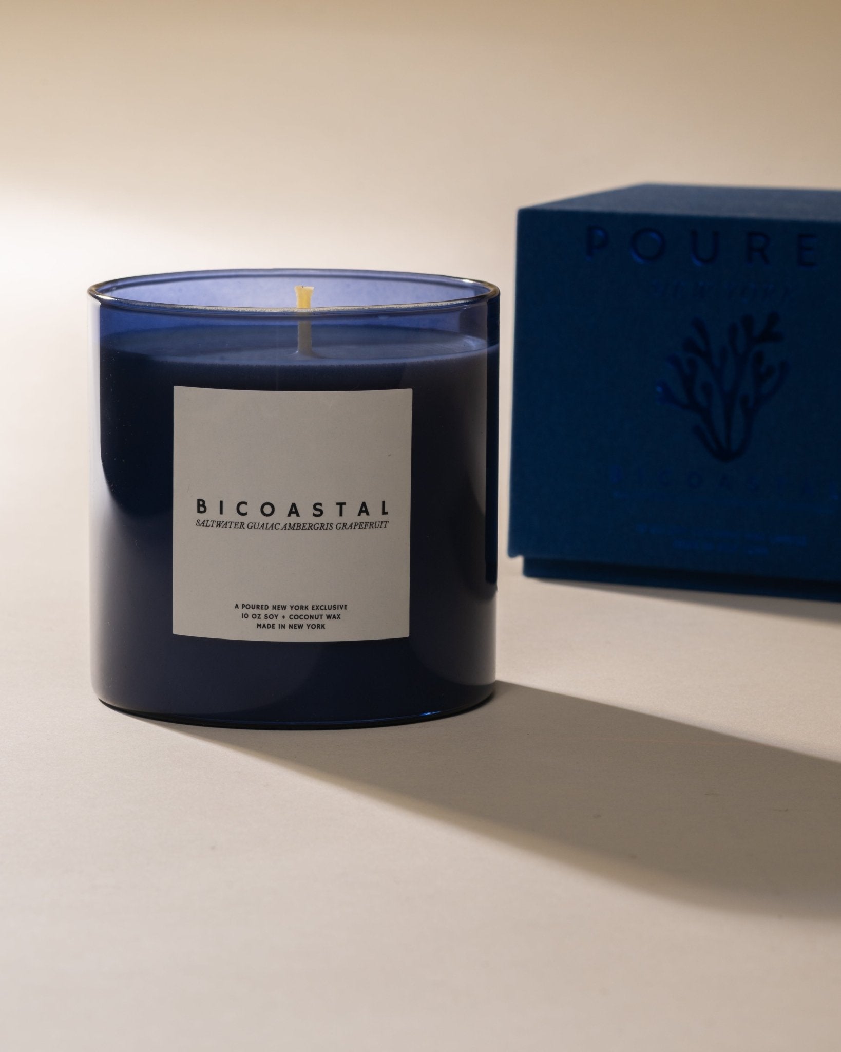 Poured New York 'Bicoastal' blue candle with a label next to a blue box on a light background