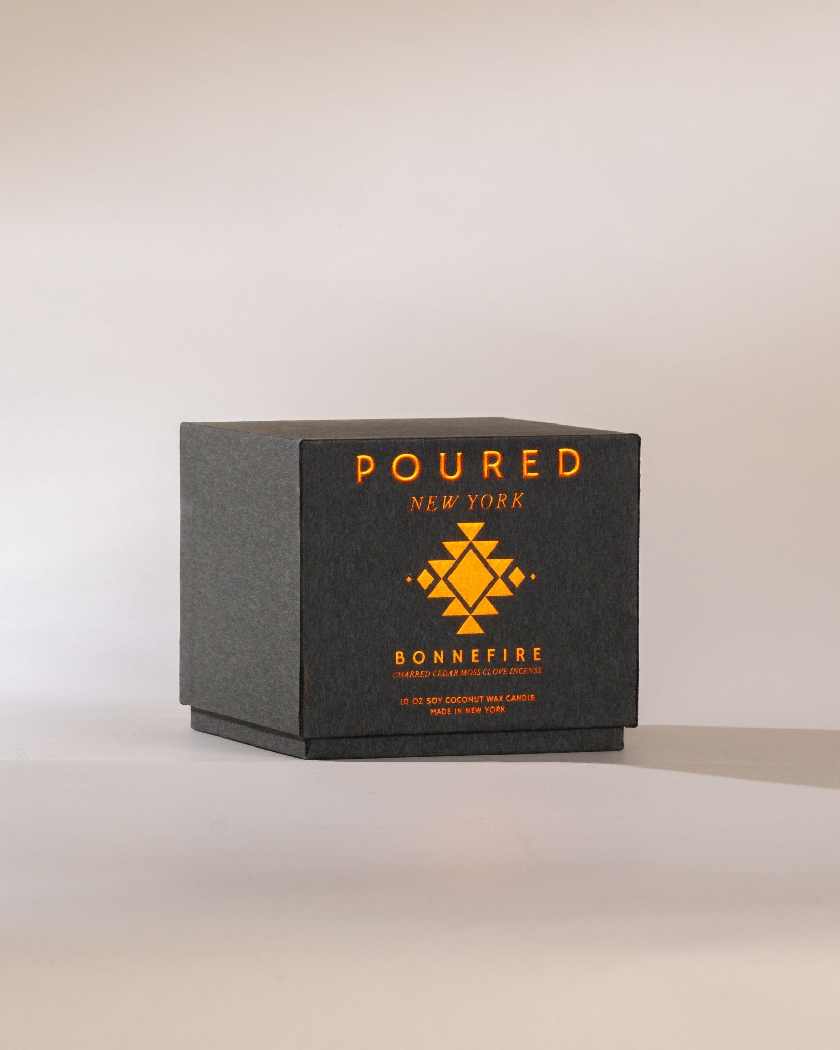 Heather grey Poured New York 'Bonnefire' candle box with orange metallic font on a neutral background