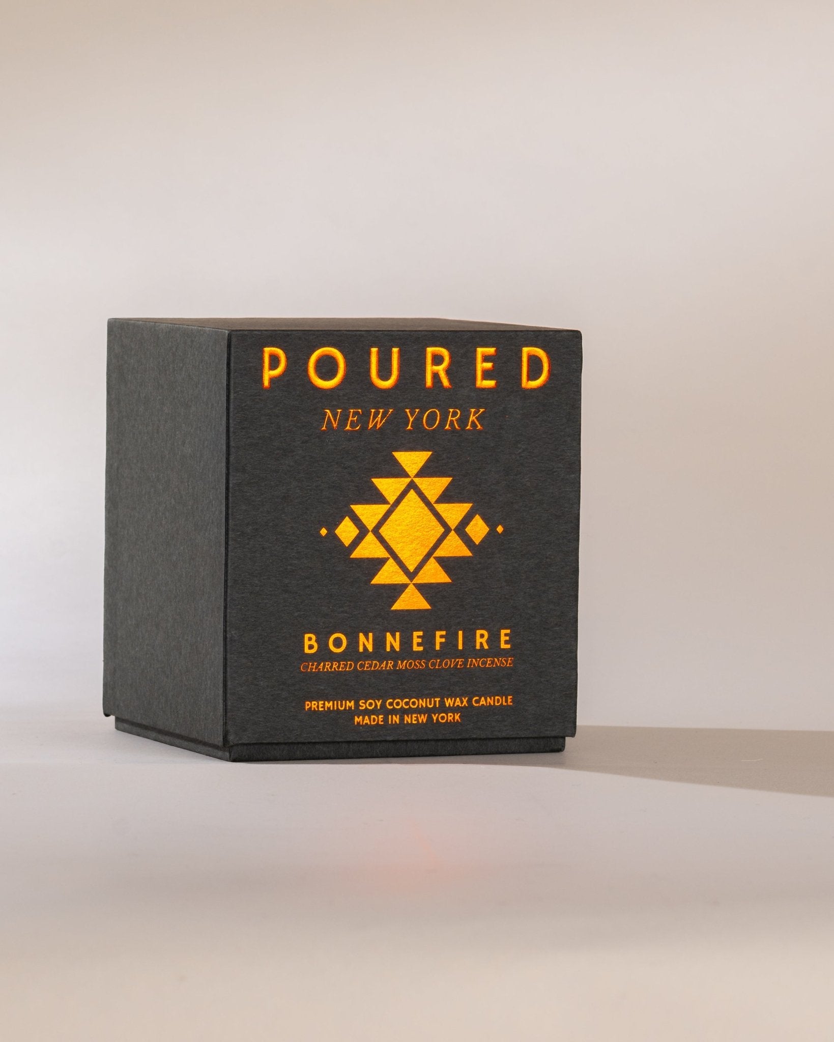 Heather grey Poured New York 'Bonnefire' two wick candle box with orange metallic font on a neutral background