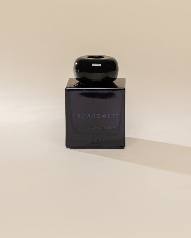 Poured New York 'Cedarsweet' 3.4 fl oz reed diffuser in a navy glass vessel on a neutral background
