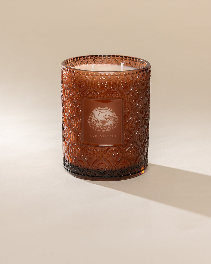 Poured New York 'Curiositeas' 22 oz brown glass vintage etched double wick candle on a neutral background
