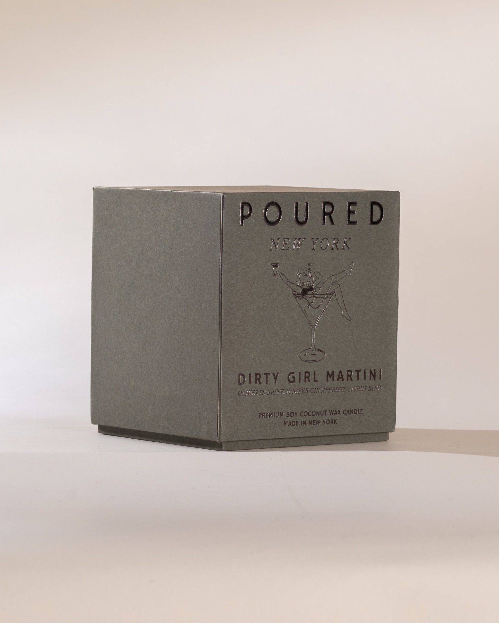 Poured New York 'Dirty Girl Martini' candle box with a girl in a martini glass decal on a neutral background