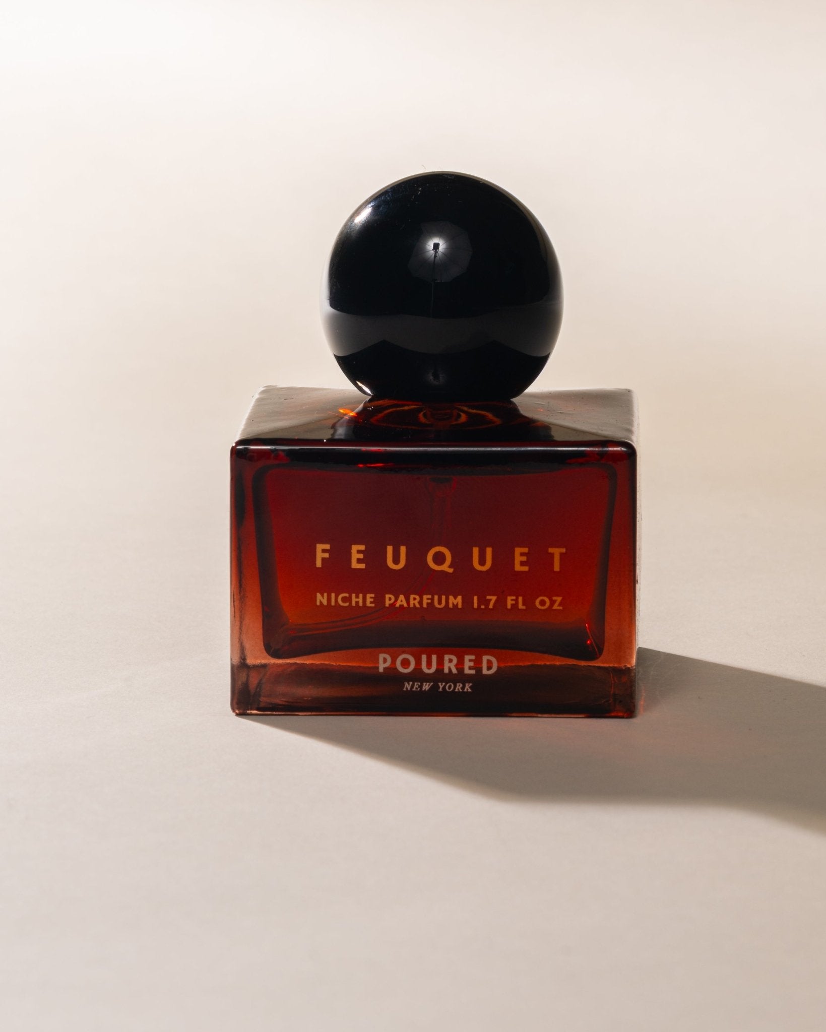 Feuquet perfume bottle with black cap on a beige background