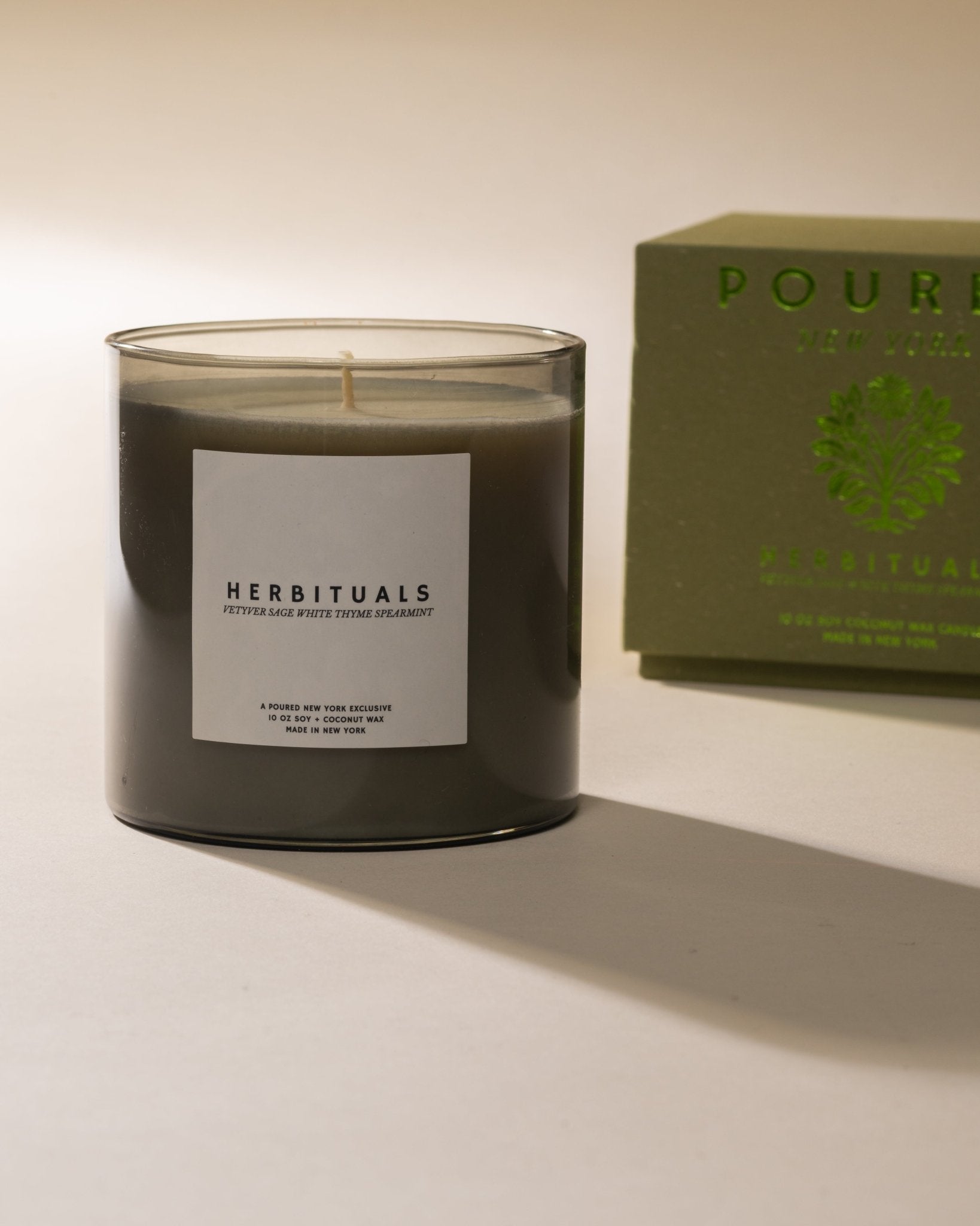 Poured New York 'Herbituals' sage green candle with a matching box on a neutral background