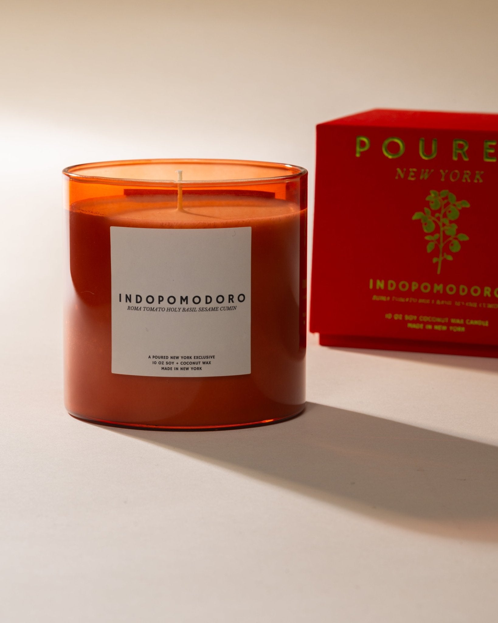 Poured New York 'Indopomodoro' tomato red glass candle with a matching red candle box with tomato vine decal on neutral background