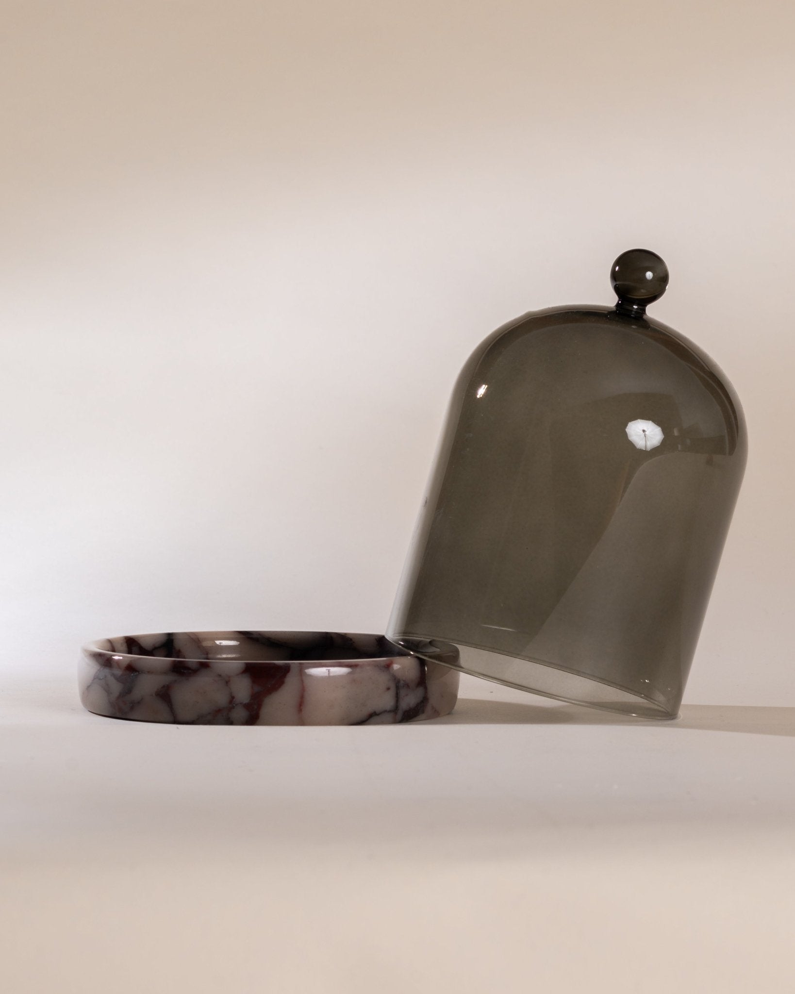 Smoked grey glass cloche with purple marbled base on a white background