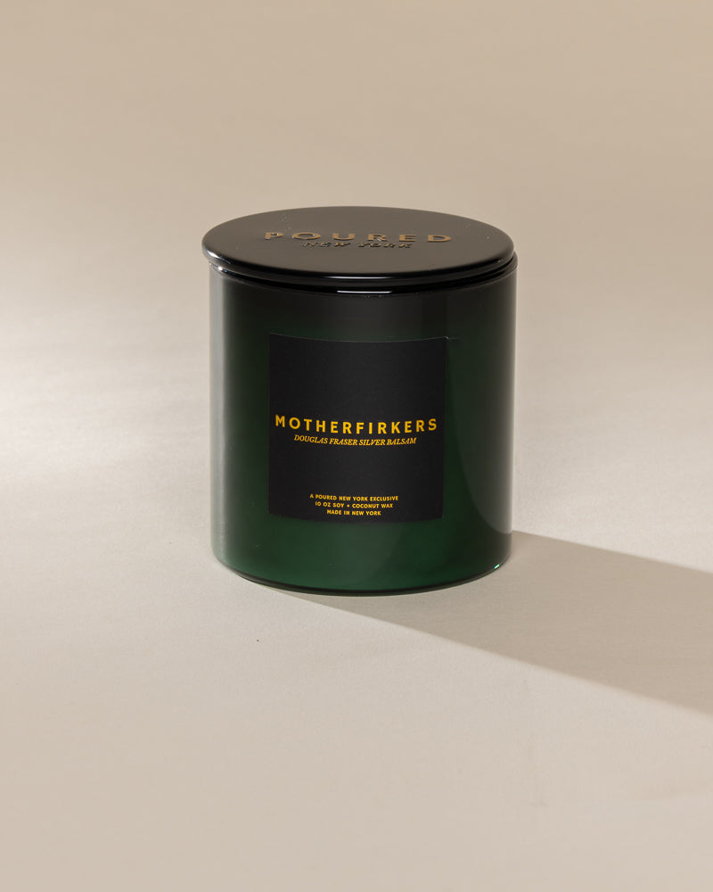 Poured New York 'Motherfirkers' 10 oz green glass soy wax candle on a neutral background