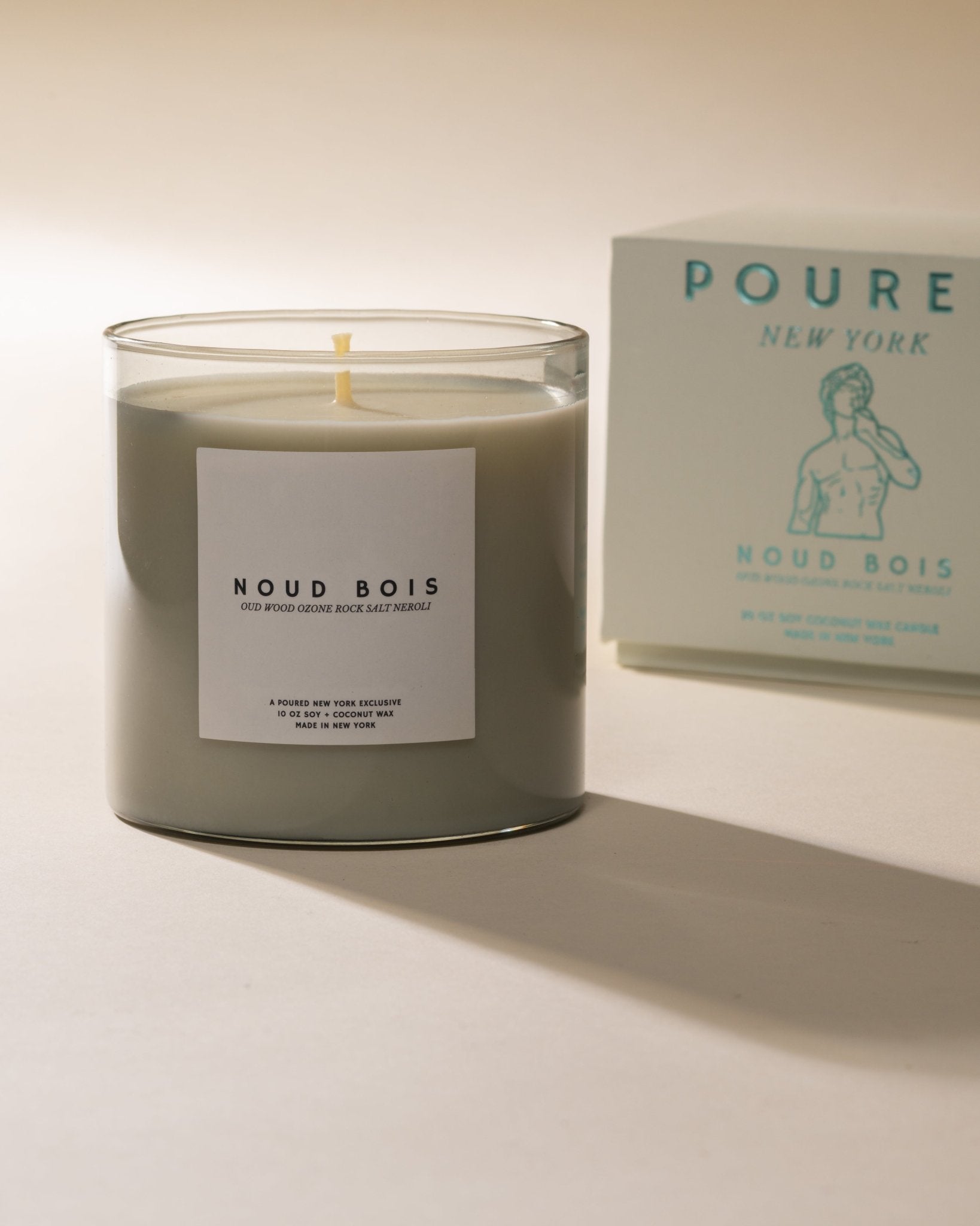 Candle labeled 'Noud Bois' with a box in the background on a light background