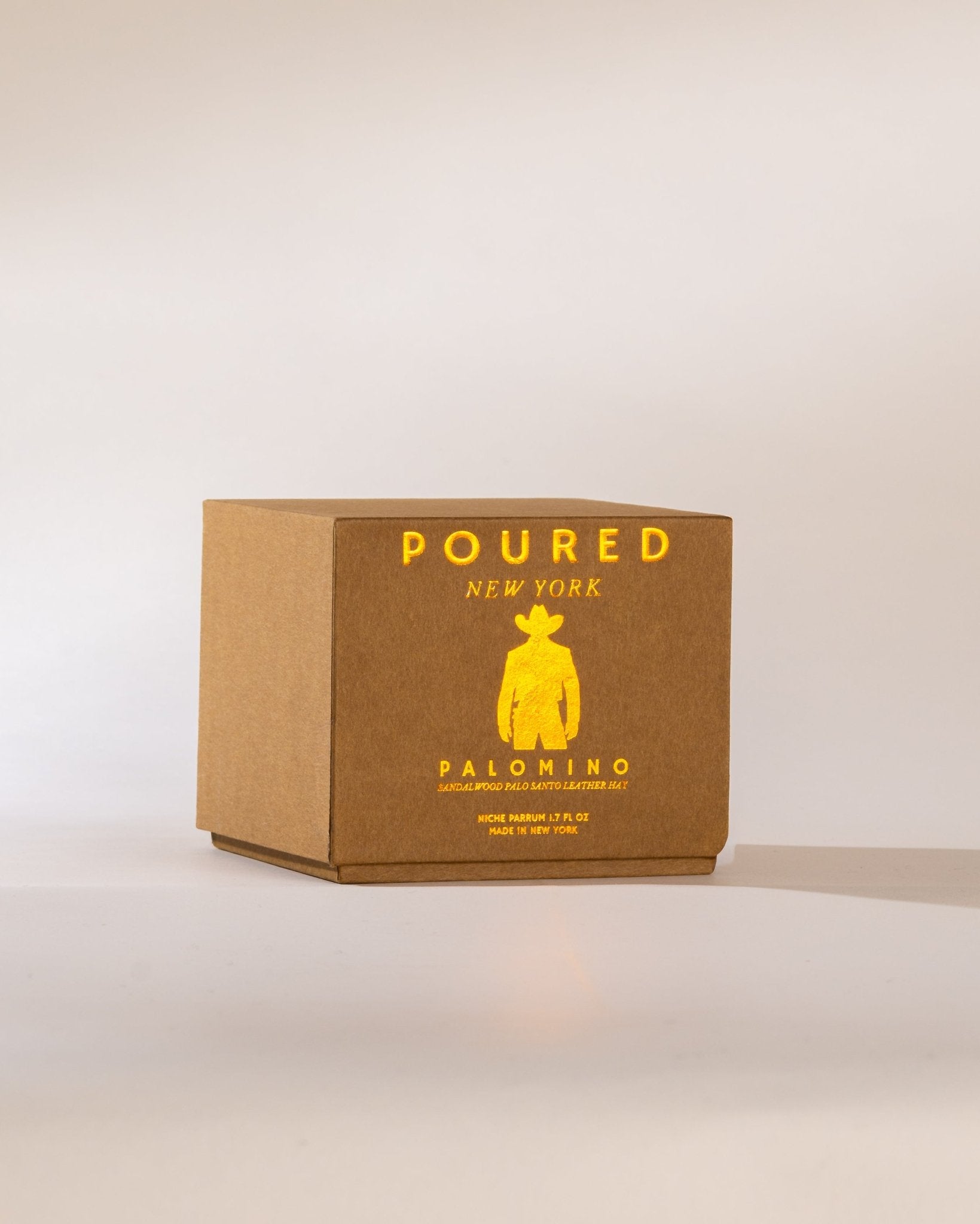 Brown box with gold foil text and cowboy logo on a neutral background