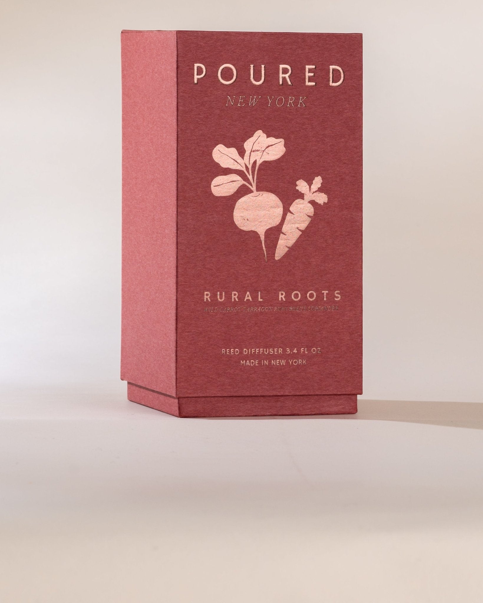 Red box with POURED NEW YORK 'RURAL ROOTS' Reed Diffuser box on a beige background