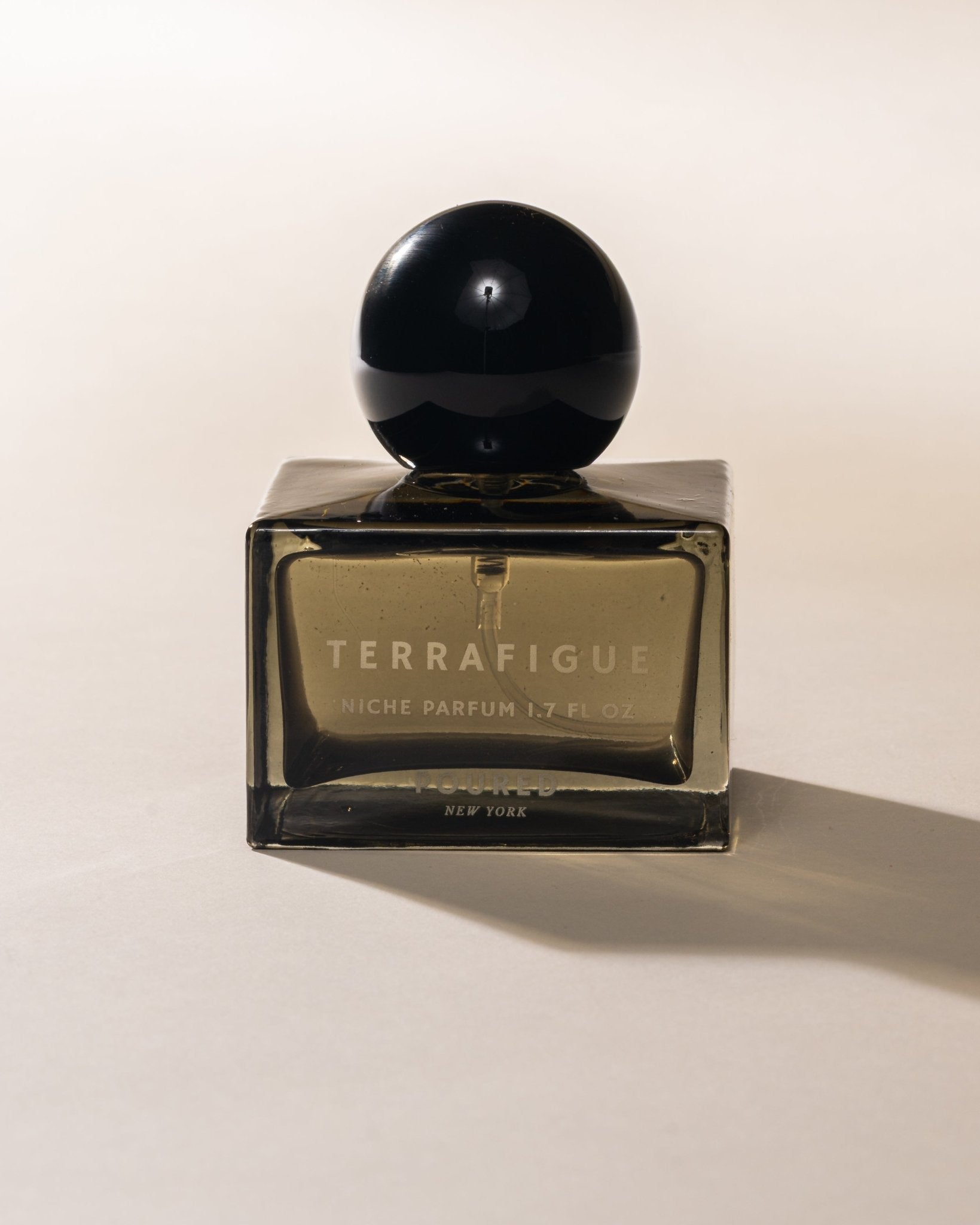 Poured New York 'Terrafigue' niche parfum square olive green bottle with black cap on a light background