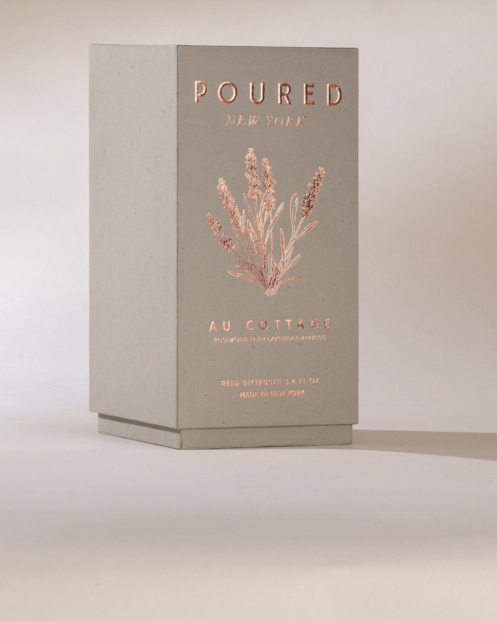Poured New York 'Au Cottage' grey reed diffuser box and lavender decal on a neutral background