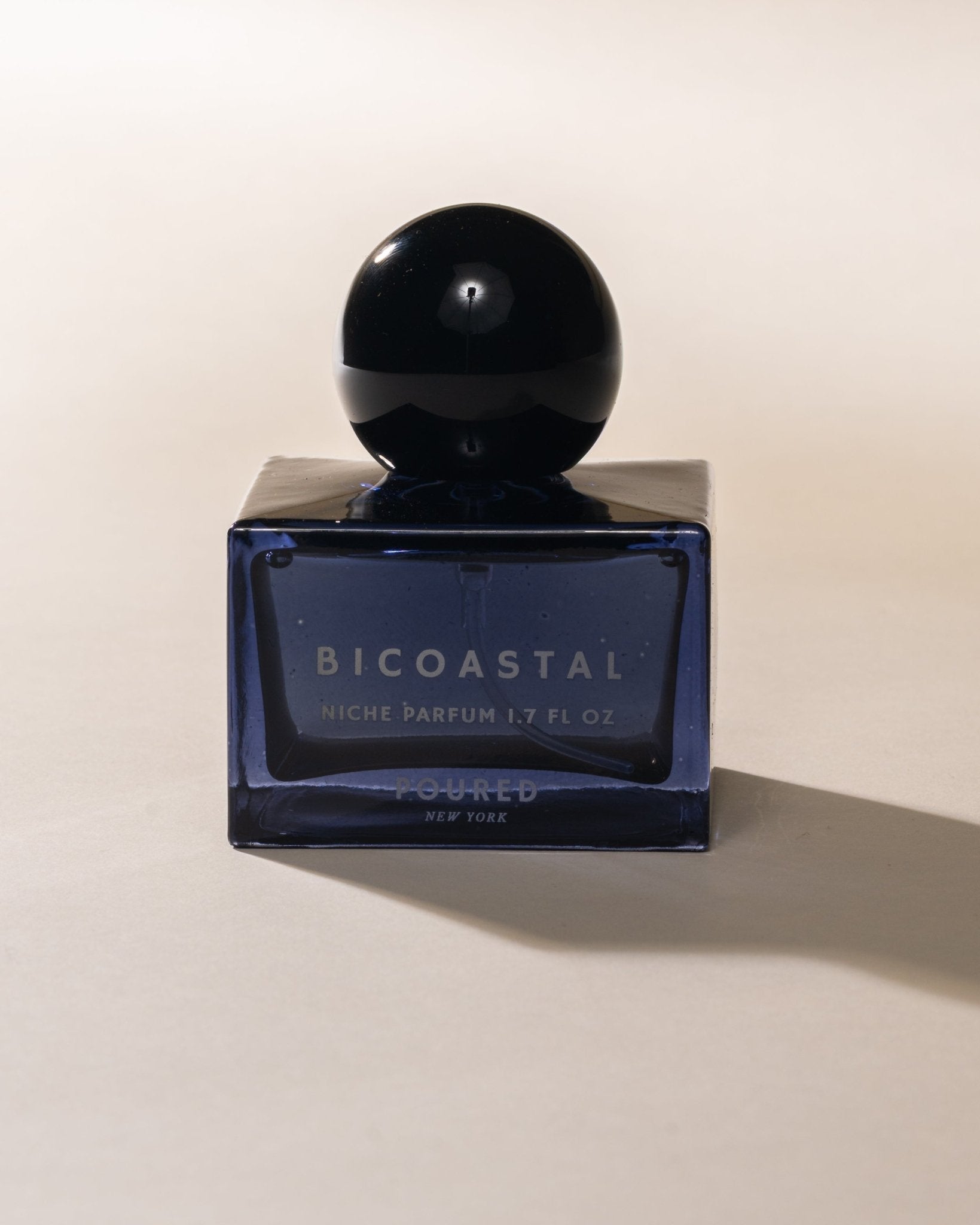 Blue Bicoastal perfume bottle on a beige background