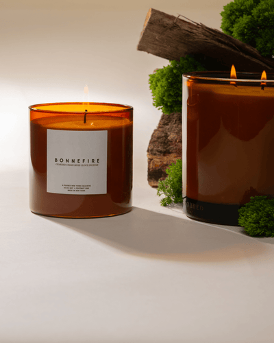 Two Poured New York lit candles with 'Bonnefire' label with moss and wood props on a neutral background