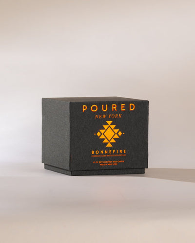 Heather grey Poured New York 'Bonnefire' candle box with orange metallic font on a neutral background
