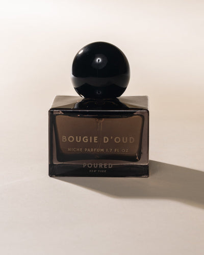 Black perfume bottle labeled 'Bougie d'Oud' on a light beige background