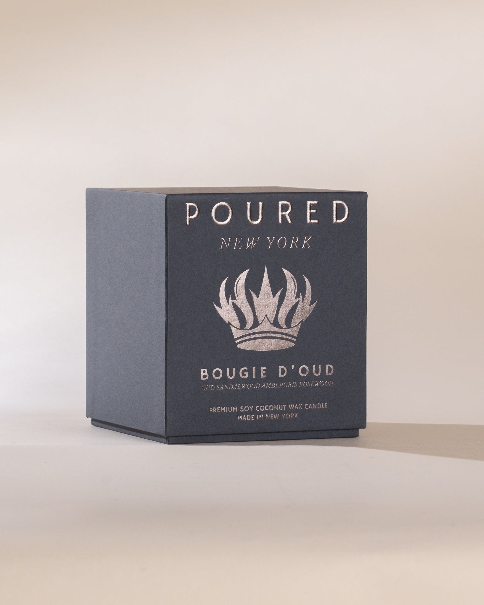 Candle packaging with 'POURED New York' branding and crown decal on a light background