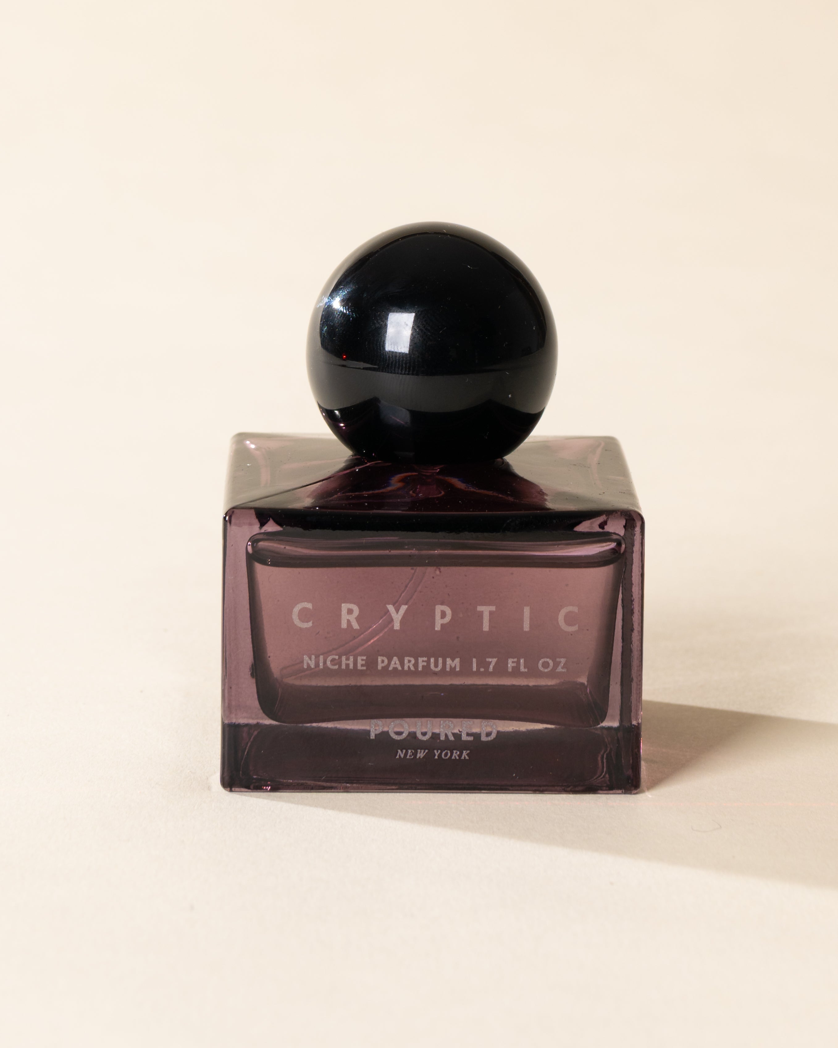 Poured New York 'Cryptic' 1.7 fl oz niche parfum in a purple glass bottle on a neutral background