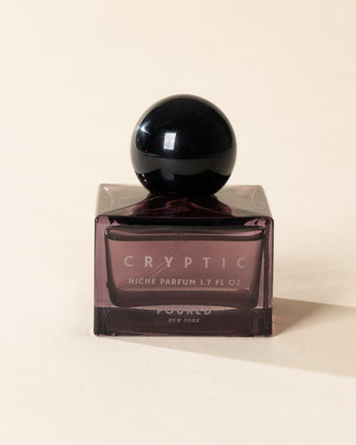 Poured New York 'Cryptic' 1.7 fl oz niche parfum in a purple glass bottle on a neutral background