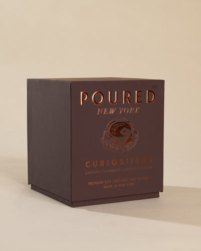 Poured New York 'Curiositeas' candle box packaging on a neutral background