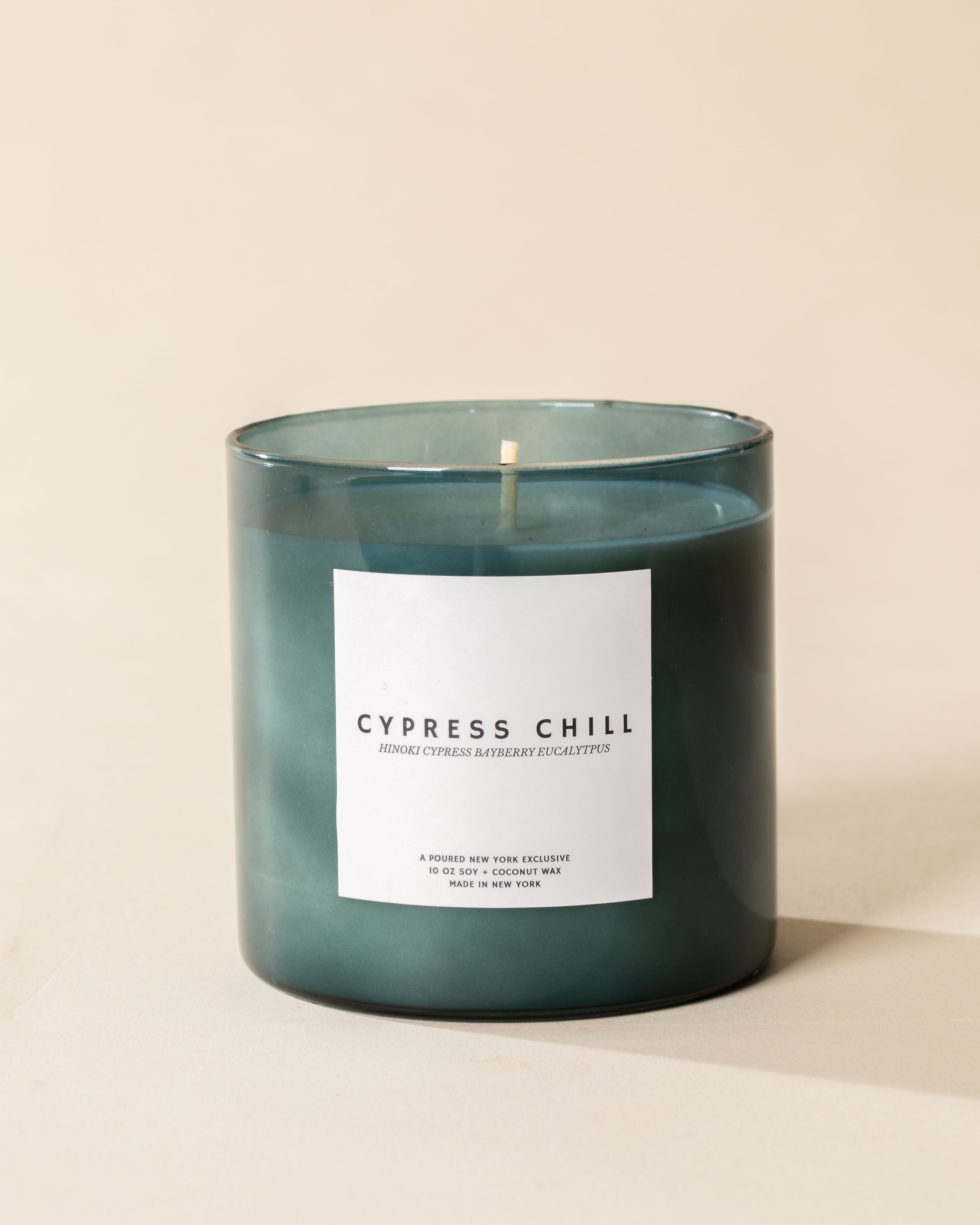 Poured New York 'Cypress Chill' 10 oz teal glass soy coconut wax candle on a neutral background