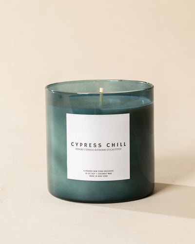 Poured New York 'Cypress Chill' 10 oz teal glass soy coconut wax candle on a neutral background