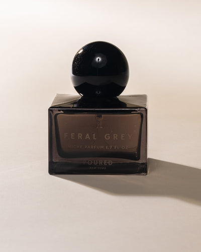 Poured New York 'Feral Grey' grey square niche parfum bottle with a black circular cap on a neutral background.