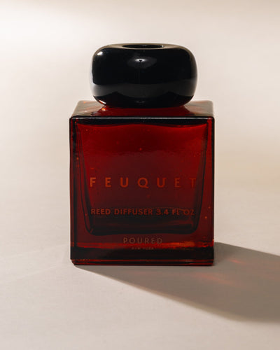 Red FEUQUET reed diffuser bottle with black cap on a white background