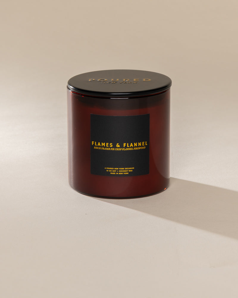 Poured New York 'Flames & Flannel' 10 oz red glass soy wax candle on a neutral background
