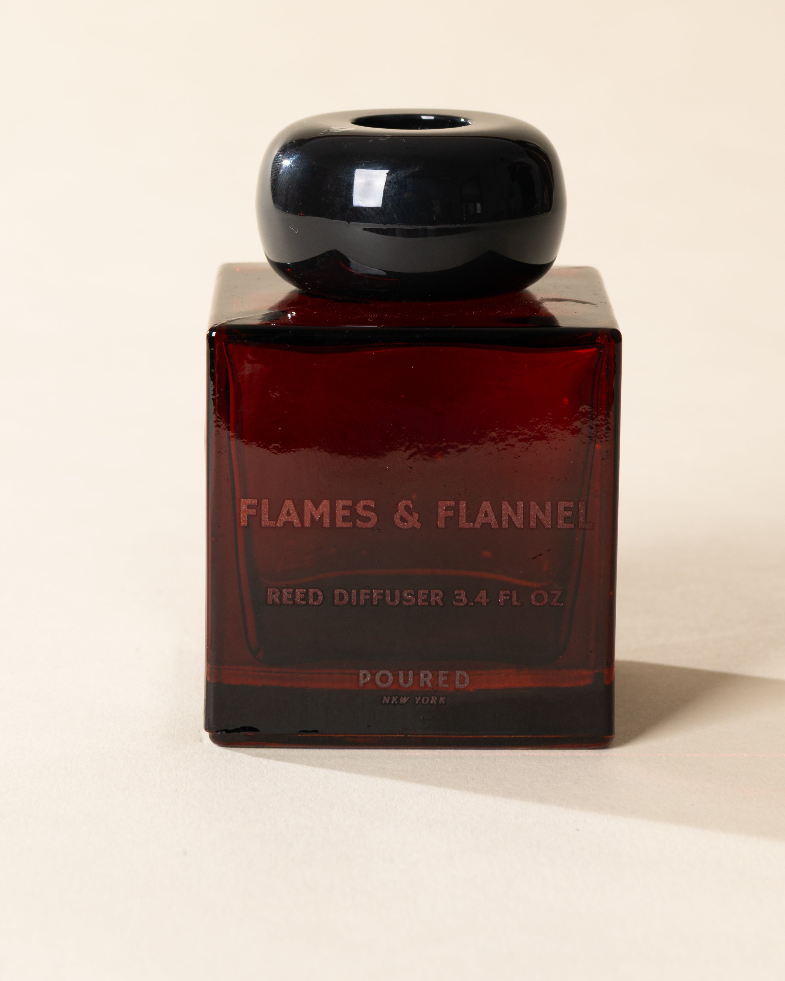 Poured New York 'Flames & Flannel' 3.4 fl oz reed diffuser in a red glass vessel on a neutral background