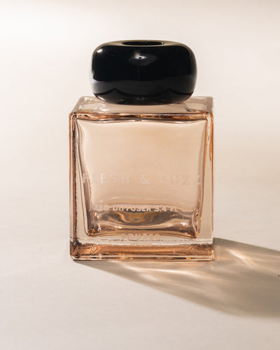 Poured New York reed diffuser labeled 'Flesh & Fuzz' in a peach square glass and black cap on a neutral background