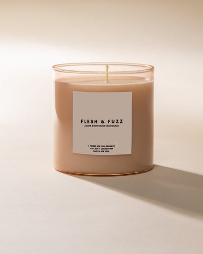 Poured New York 10 oz candle labeled 'Flesh & Fuzz' in a peach glass on a neutral background