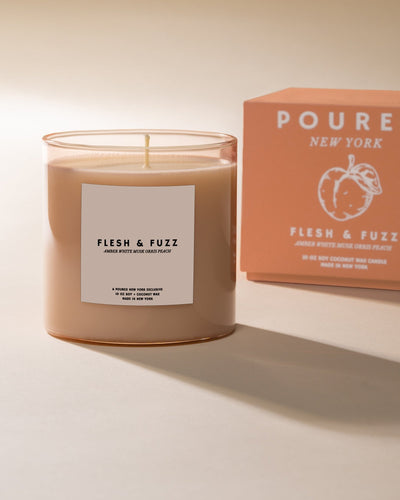 Candle labeled 'Flesh & Fuzz' with a matching box on a neutral background