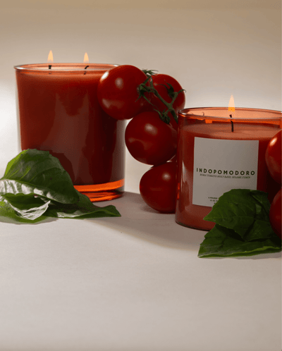 Two Poured New York 'Indopomodoro' candles with fresh Roma tomatoes and basil decor on a neutral background