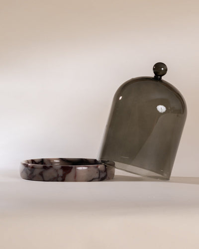 Smoked grey glass cloche with purple marbled base on a white background