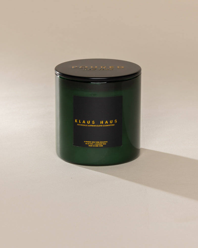 Poured New York 'Klaus Haus' 10 oz green glass coconut soy wax candle on a neutral background