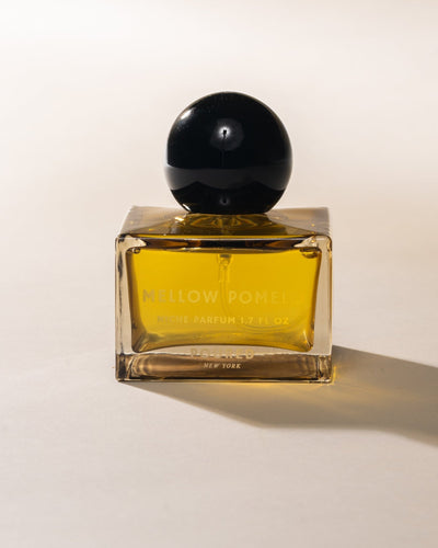 Poured New York 'Mellow Pomelo' Niche Parfum square glass with circular black cap on neutral background.