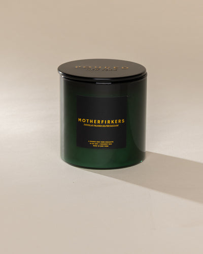 Poured New York 'Motherfirkers' 10 oz green glass soy wax candle on a neutral background