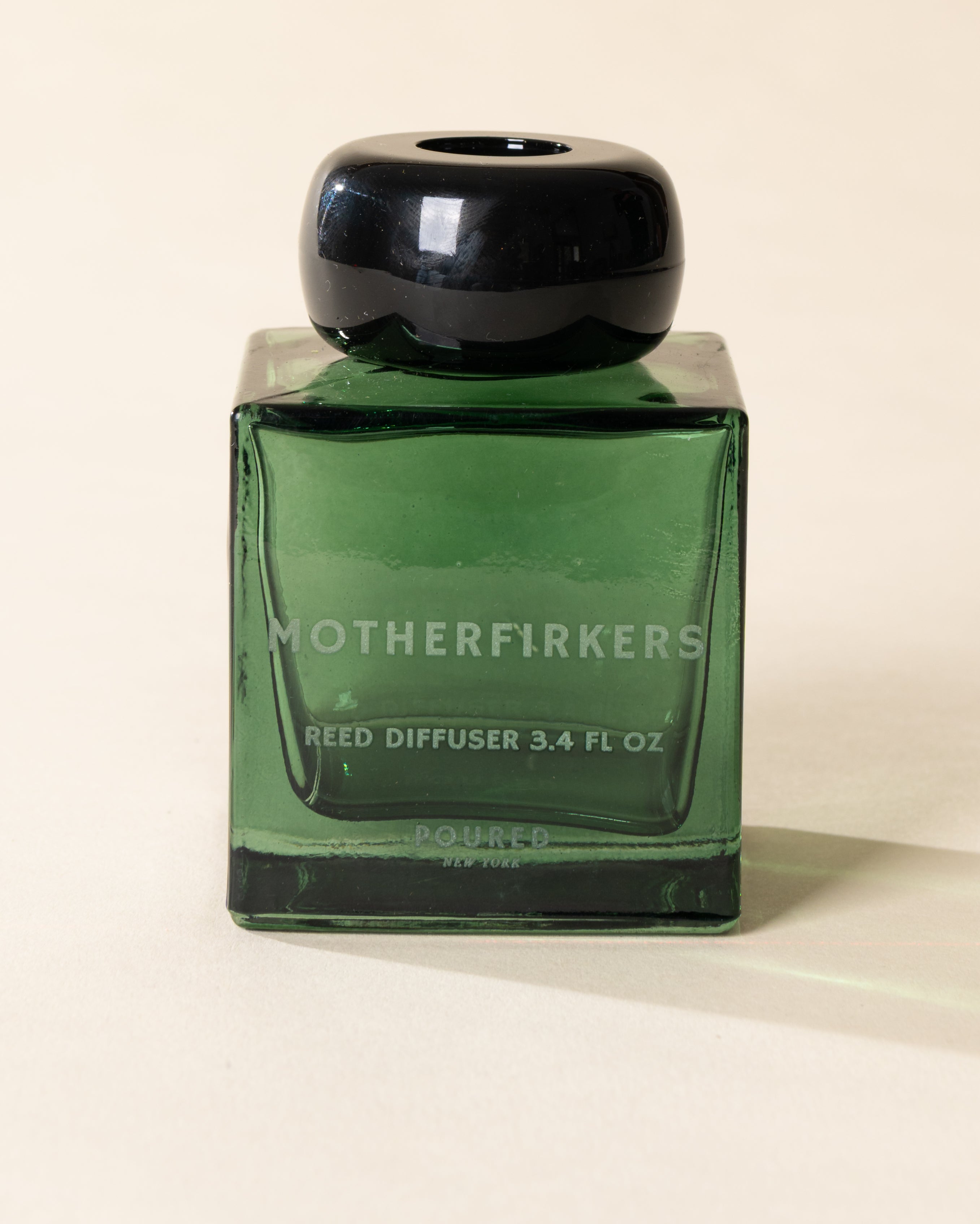 Poured New York 'Motherfirkers' 3.4 fl oz reed diffuser in a green glass vessel on a neutral background