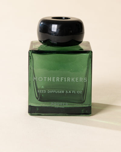 Poured New York 'Motherfirkers' 3.4 fl oz reed diffuser in a green glass vessel on a neutral background