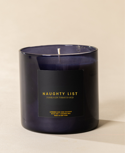 Poured New York 'Naughty List' 10 oz navy glass soy wax candle on a neutral background