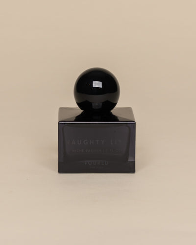 Poured New York 'Naughty List' 1.7 fl oz niche parfum in a navy glass bottle on a neutral background