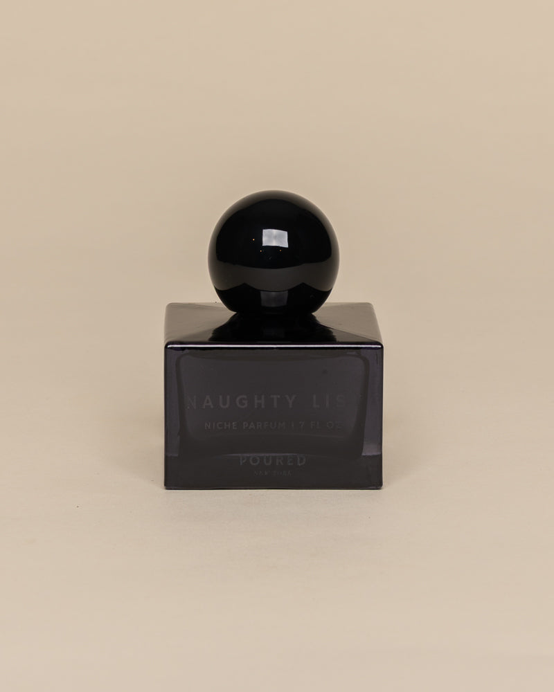 Poured New York 'Naughty List' 1.7 fl oz niche parfum in a navy glass bottle on a neutral background