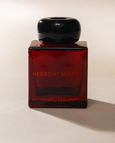 Poured New York 'Negroni Nights' red square reed diffuser on a neutral background.
