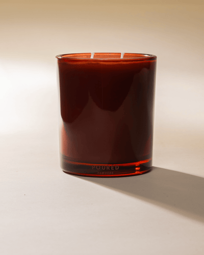 Poured New York 'Negroni Nights' two wick candle in red glass jar on a neutral background.