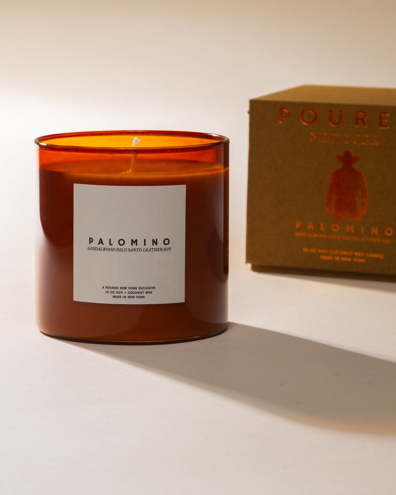 Poured New York candle labeled 'Palomino' with a matching box with a cowboy icon on a light background